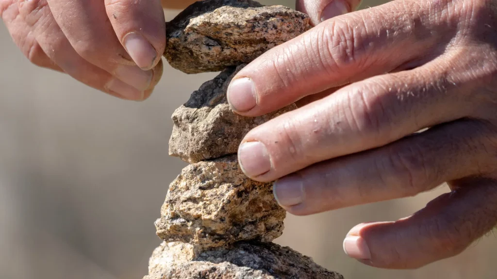 Hands Building a Stone Cairn