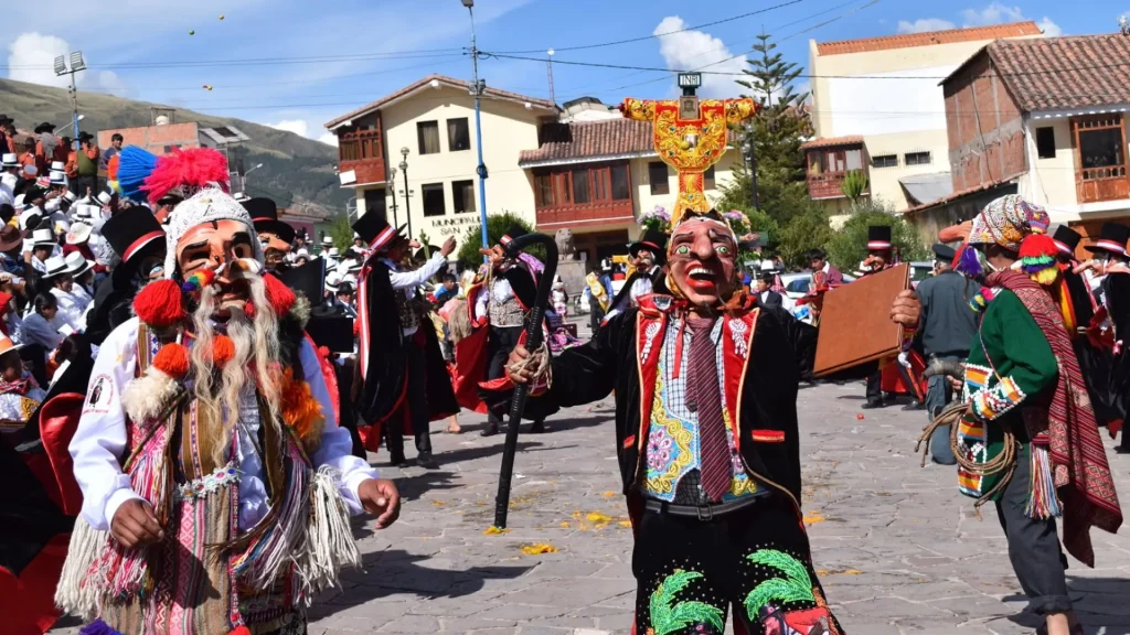 Masked dancers performing in Andean plaza during cultural celebration